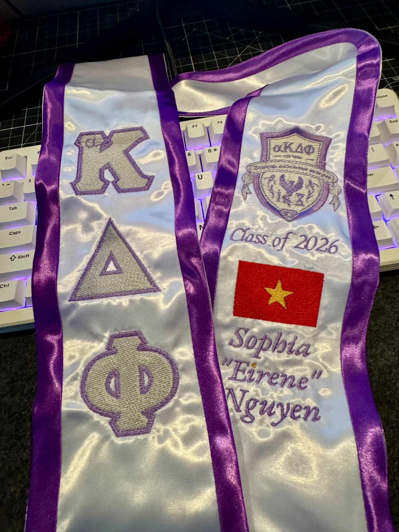 Graduation stole embroidered with Greek letters and a sorority crest