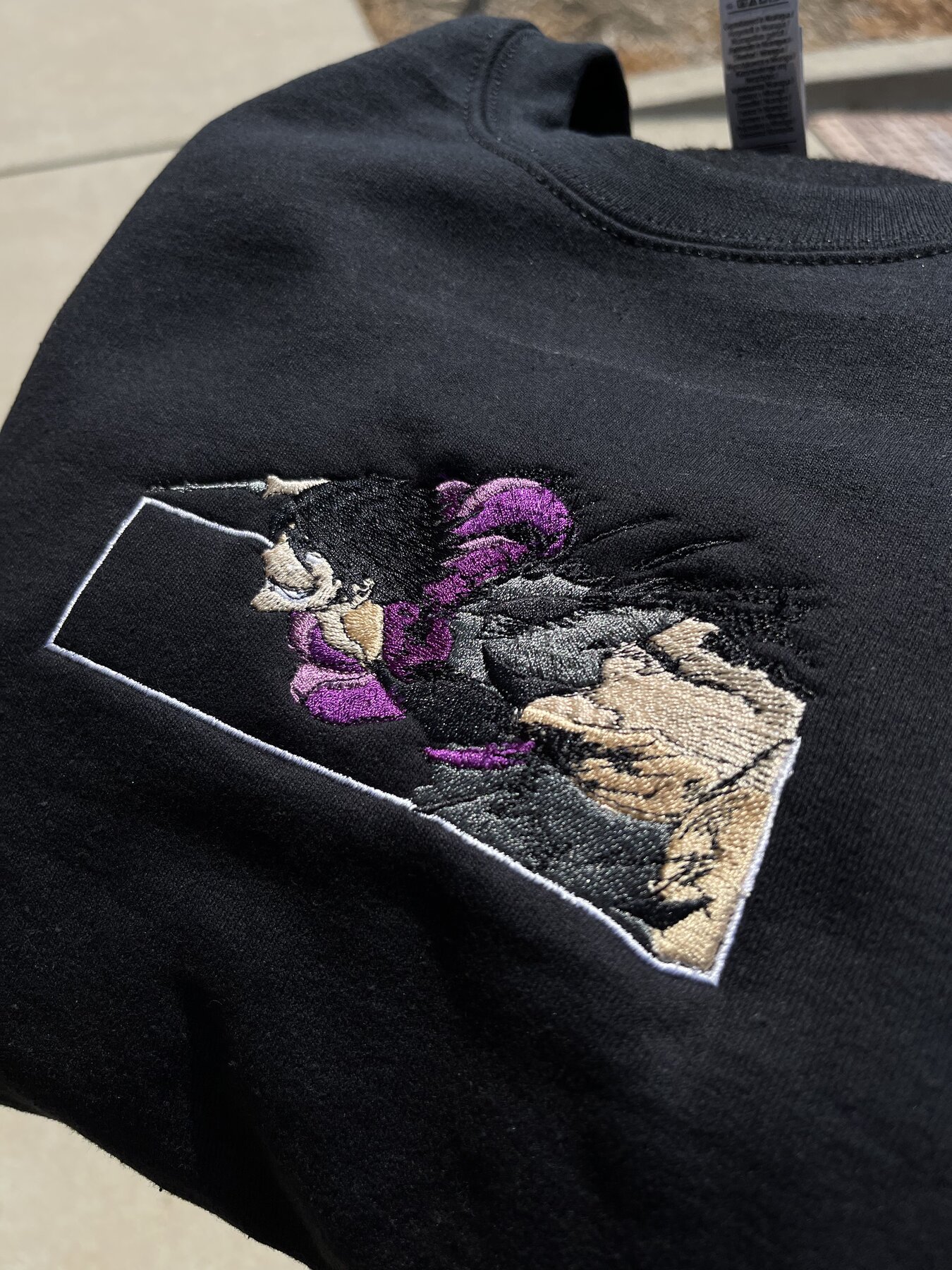 Anime-style character patch embroidered on a black sweatshirt sleeve