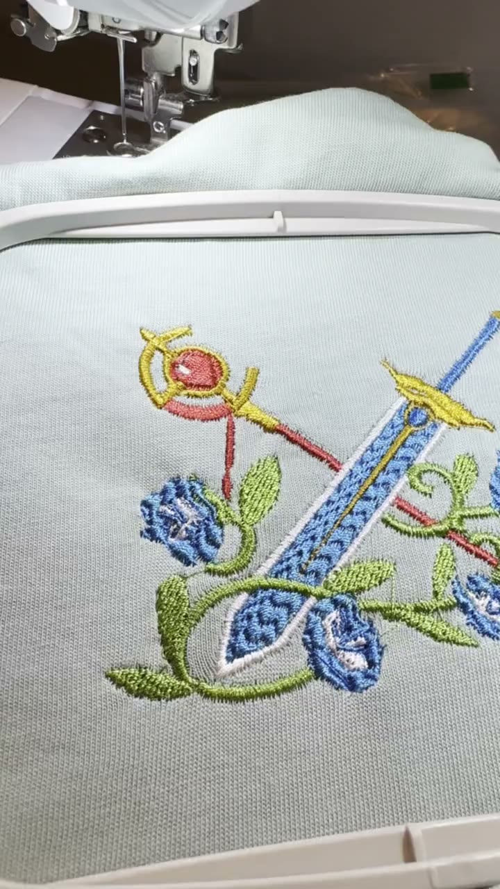 Sword and rose crest design in the embroidery hoop, mid-stitch